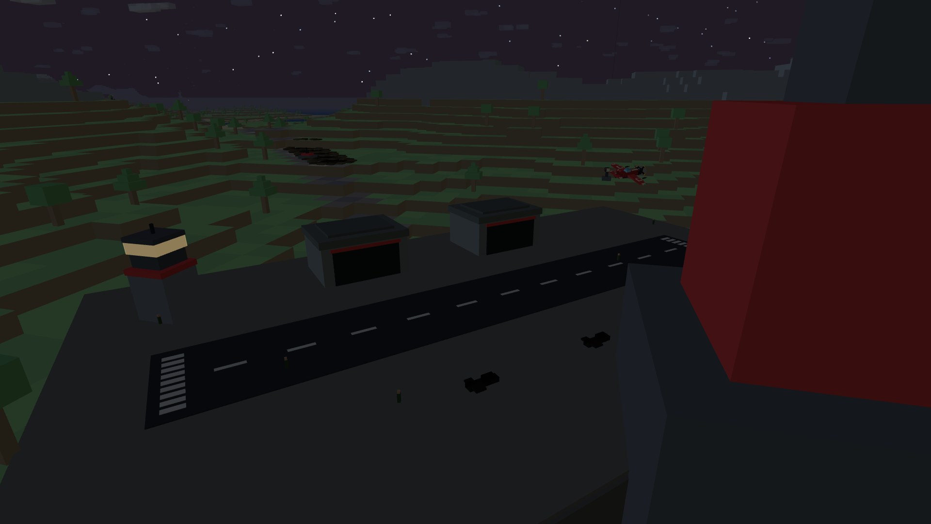 A control tower with a lit amber window band glowing at dusk beside an orange windsock, ground crew scattered across the field under a star-flecked sky